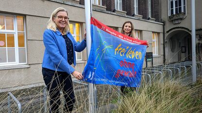Zum Aktionstag gegen Gewalt an Frauen haben die Gleichstellungsbeauftragte Darja Petrosjan und Oberbürgermeisterin Petra Gerlach vor dem Rathaus eine Fahne gehisst. | Bild: Fiedler